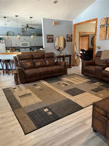 Living room with light wood-type flooring, ceiling fan, and lofted ceiling