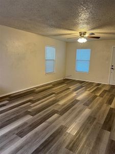 Empty room with dark wood-type flooring, a textured ceiling, and ceiling fan