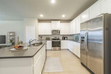 Kitchen featuring a kitchen island with sink, white cabinetry, stainless steel appliances, sink, and light hardwood / wood-style floors