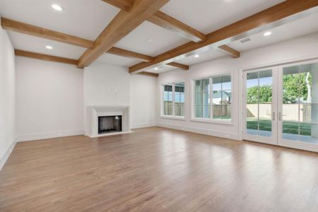 Unfurnished living room featuring light hardwood / wood-style floors, coffered ceiling, french doors, and beamed ceiling