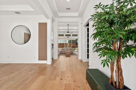 Hallway featuring a raised ceiling and light hardwood / wood-style flooring