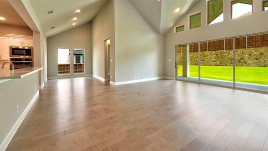 Unfurnished living room with hardwood / wood-style floors, a wealth of natural light, and high vaulted ceiling