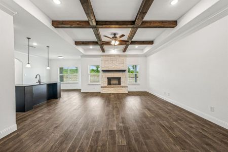 Unfurnished living room with ceiling fan, a fireplace, dark wood-type flooring, and coffered ceiling