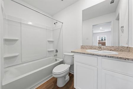 Primary bathroom includes granite counters, designer white cabinetry and luxury vinyl plank flooring.