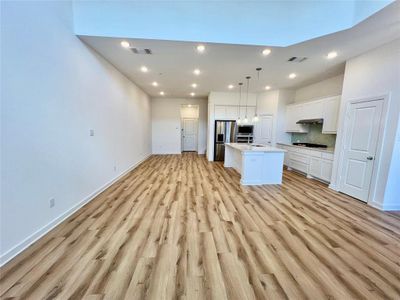 Kitchen with stainless steel appliances, pendant lighting, light wood-type flooring, and a kitchen island with sink