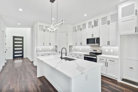 Kitchen with stainless steel appliances, a center island with sink, sink, and white cabinetry