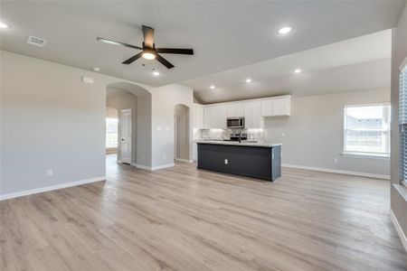 Kitchen featuring white cabinetry, appliances with stainless steel finishes, an island with sink, and light wood-type flooring