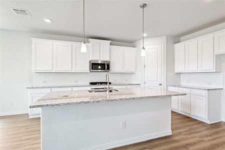 Kitchen featuring white cabinetry, hardwood / wood-style flooring, tasteful backsplash, and sink