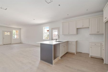 Kitchen with white cabinets, kitchen peninsula, light wood-type flooring, and sink