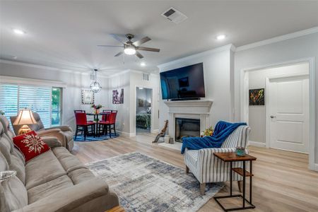 Living room featuring ceiling fan, light hardwood / wood-style floors, and crown molding