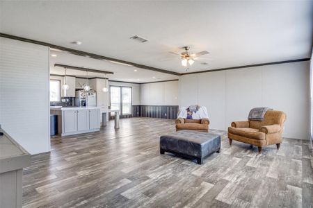 Living area featuring light wood-type flooring, ceiling fan, and crown molding