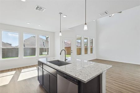 Kitchen with dishwasher, a kitchen island with sink, wood-type flooring, sink, and decorative light fixtures