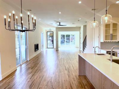 Kitchen featuring light hardwood floors, tasteful backsplash, pendant lighting, light stone counters, and sink
