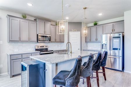 Kitchen featuring a kitchen breakfast bar, stainless steel appliances, decorative light fixtures, and sink