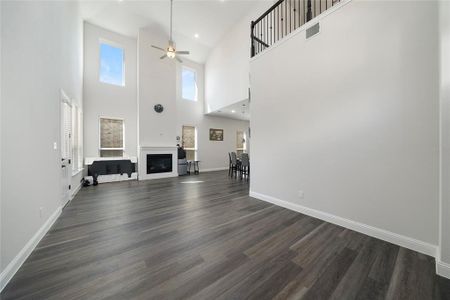 Unfurnished living room featuring high vaulted ceiling, ceiling fan, and dark wood-type flooring