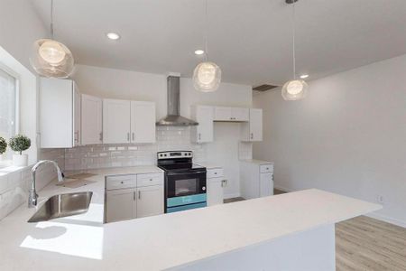 Kitchen featuring light wood-type flooring, white cabinetry, sink, wall chimney range hood, and electric stove