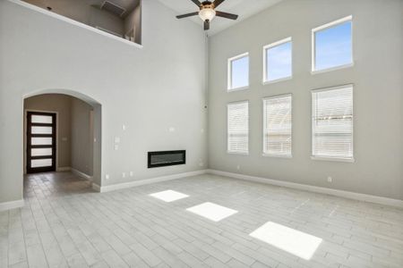 Unfurnished living room featuring light hardwood / wood-style floors, a towering ceiling, and ceiling fan