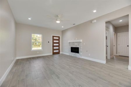 Unfurnished living room featuring a fireplace, ceiling fan, and light hardwood / ceramic tile wood-style floors