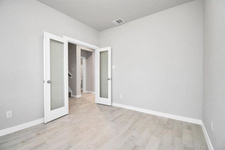 At the forefront, a refined home office beckons productivity and focus. Luxurious details like tile flooring, custom paint, expansive windows with privacy blinds, and French doors create an inspiring workspace. Sample photo of completed home with similar floor plan. Actual colors and selections may vary.