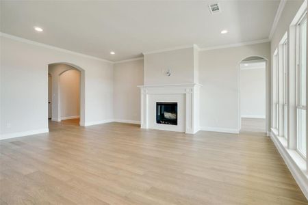 Unfurnished living room with light wood-type flooring and ornamental molding