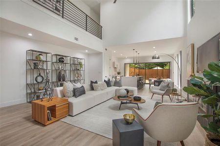 Living room with a towering ceiling and light hardwood / wood-style floors