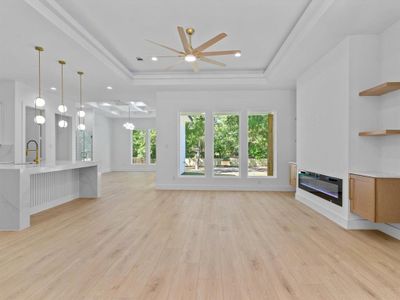 Unfurnished living room featuring ceiling fan, light hardwood / wood-style flooring, and a tray ceiling