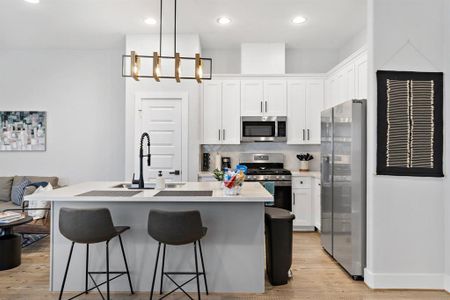 Ultra-modern kitchen equipped with top-tier appliances, white minimalist cabinetry, and a grand island serving as both prep and social hub.