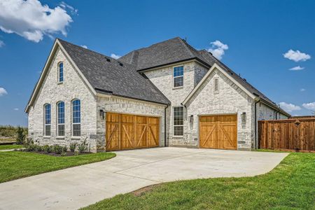 French country inspired facade featuring a garage and a front yard