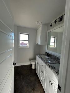 Bathroom with concrete floors, toilet, plenty of natural light, and double vanity