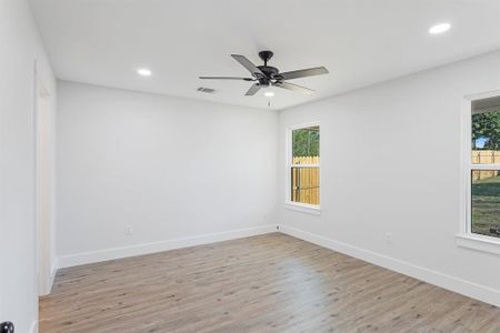 Empty room with light wood-type flooring, ceiling fan, and plenty of natural light