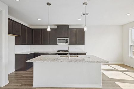 Kitchen with light hardwood / wood-style floors, a center island with sink, stainless steel appliances, and sink