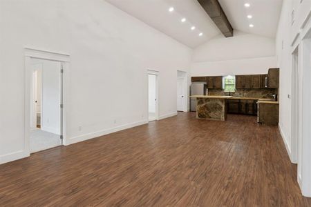 Unfurnished living room featuring dark hardwood / wood-style floors, beam ceiling, and high vaulted ceiling