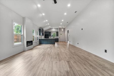 Unfurnished living room featuring light hardwood / wood-style flooring, lofted ceiling, and ceiling fan