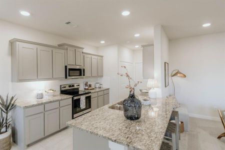 Kitchen featuring light stone countertops, appliances with stainless steel finishes, and a kitchen breakfast bar