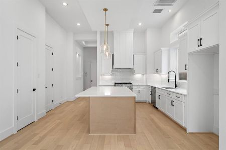 Another view of the impressive island kitchen with stylish pendant lighting and high-end finishes.