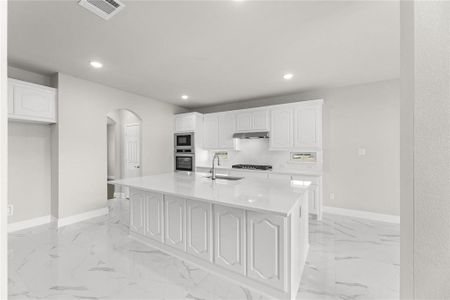 Kitchen with appliances with stainless steel finishes, a center island with sink, sink, and white cabinets