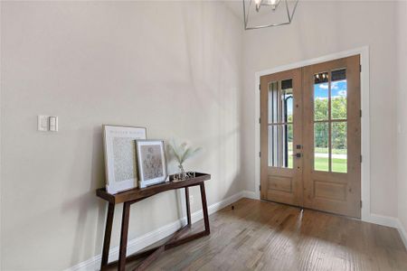 Foyer entrance featuring french doors, wood-type flooring, and an inviting chandelier