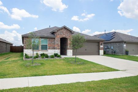 Ranch-style home with a garage, a front lawn, and solar panels