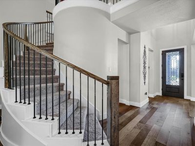 Foyer with a textured ceiling, dark wood-type flooring, and a high ceiling