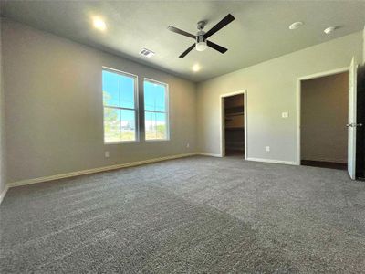 Unfurnished bedroom featuring carpet floors, a walk in closet, a closet, and ceiling fan