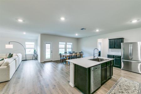 Kitchen featuring stainless steel appliances, sink, light wood-type flooring, and a kitchen island with sink