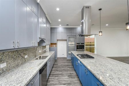 Beautiful modern kitchen with granite counters, metallic hardware and pendants, stylish pantry door, built-in appliances, and a blue island that adds pop to the space.