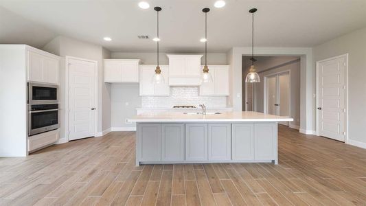 Kitchen with white cabinetry, light wood-type flooring, stainless steel oven, black microwave, and decorative backsplash