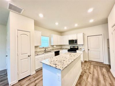 Kitchen featuring white cabinets, light hardwood / wood-style floors, stainless steel appliances, a center island, and sink