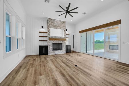 Unfurnished living room featuring light hardwood / wood-style floors, ornamental molding, a fireplace, and ceiling fan