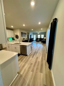 Kitchen with dishwasher, light hardwood / wood-style floors, a center island, sink, and white cabinets