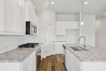 Kitchen featuring decorative light fixtures, stainless steel appliances, sink, dark wood-type flooring, and white cabinets