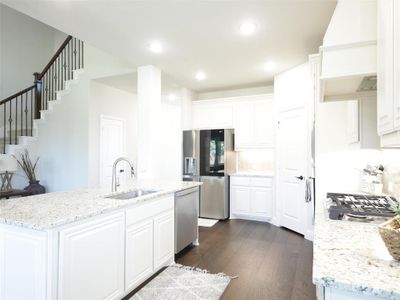 Kitchen featuring light stone counters, white cabinets, sink, appliances with stainless steel finishes, and dark hardwood / wood-style floors