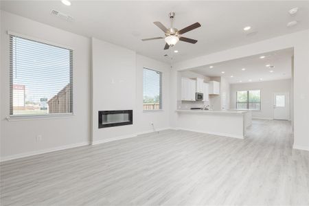 Unfurnished living room with light hardwood / wood-style floors, heating unit, and ceiling fan