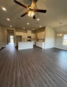 Unfurnished living room with ceiling fan with notable chandelier, lofted ceiling, dark hardwood / wood-style floors, and sink